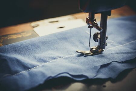 Old sewing machine, the man who sews on it, in dark colors