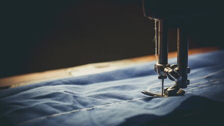 Old sewing machine, the man who sews on it, in dark colorsの写真素材