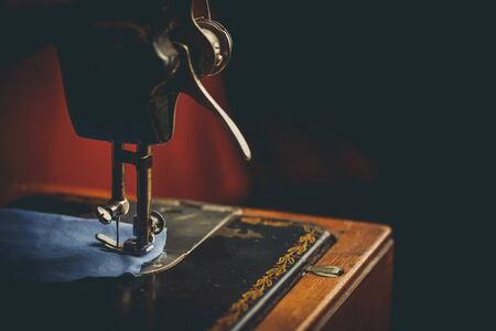 Old sewing machine, the man who sews on it, in dark colorsの写真素材