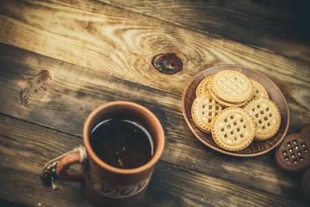 Round sweet cookies and a cup of tea on a wooden table in vintage styleの写真素材