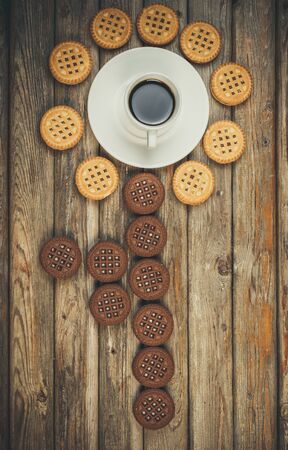 Flower of cookies and cup of coffee on a wooden background, flat layの写真素材