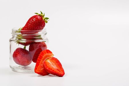 Ripe strawberries in a glass jar on a white backgroundの写真素材