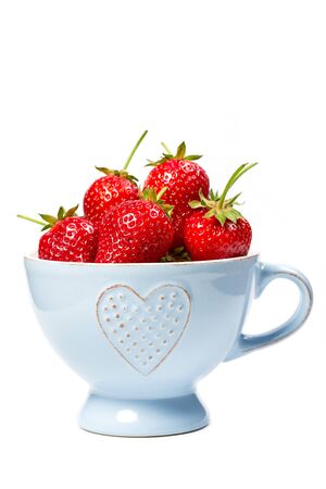 Strawberries in a blue cup on a white backgroundの写真素材