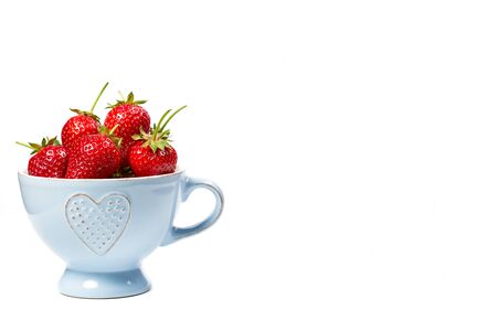 Strawberries in a blue cup on a white backgroundの写真素材