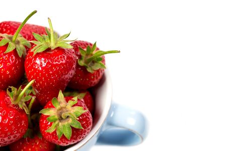 Strawberries in a blue cup on a white backgroundの写真素材