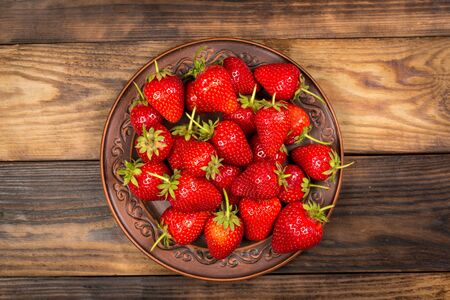 Ripe red strawberries on a brown wooden backgroundの写真素材