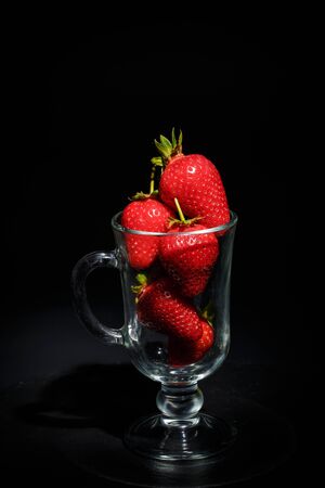 Ripe red strawberries on the dishes on a black backgroundの写真素材