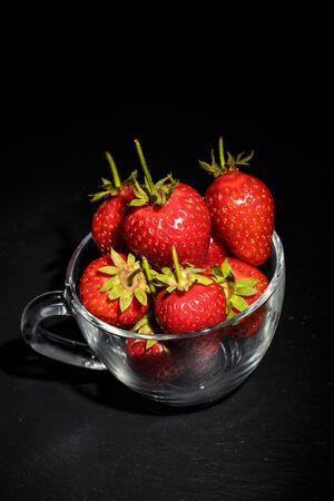 Ripe red strawberries on the dishes on a black backgroundの写真素材