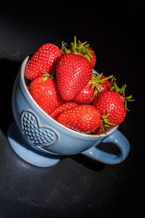 Ripe red strawberries on the dishes on a black backgroundの写真素材