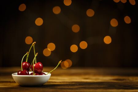 Ripe cherries on a brown table, beautiful bokehの写真素材