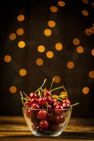 Ripe cherries on a brown table, beautiful bokehの写真素材