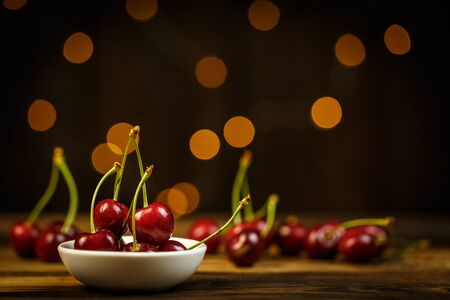 Ripe cherries on a brown table, beautiful bokehの写真素材