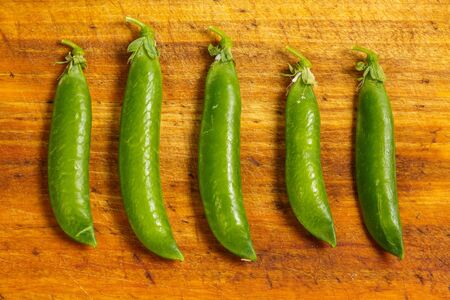 Ripe green peas on a wooden surface for cookingの写真素材