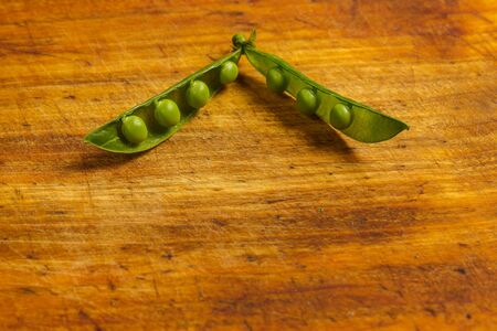 Ripe green peas on a wooden surface for cookingの写真素材