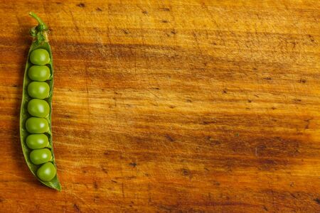 Ripe green peas on a wooden surface for cookingの写真素材