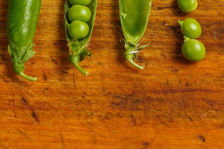 Ripe green peas on a wooden surface for cookingの写真素材