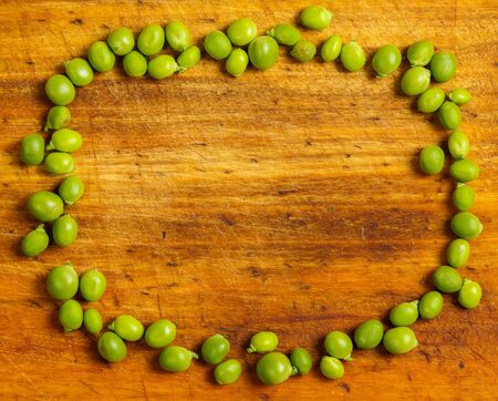 Ripe green peas on a wooden surface for cookingの写真素材