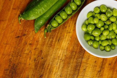 Ripe green peas on a wooden surface for cookingの写真素材
