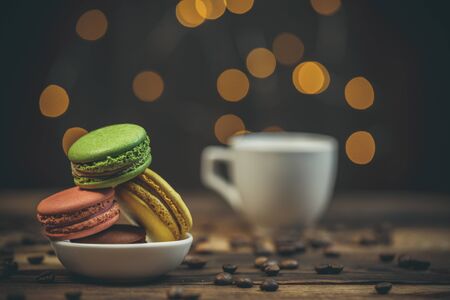 Tasty macaroon cookies with coffee on a wooden table in warm color with beautiful bokehの写真素材