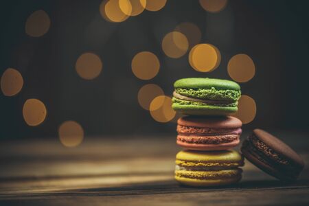 Tasty macaroon cookies with coffee on a wooden table in warm color with beautiful bokehの写真素材