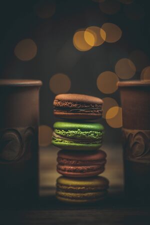 Tasty macaroon cookies with coffee on a wooden table in warm color with beautiful bokehの写真素材