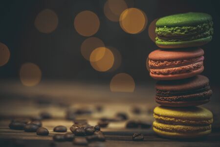 Tasty macaroon cookies with coffee on a wooden table in warm color with beautiful bokehの写真素材