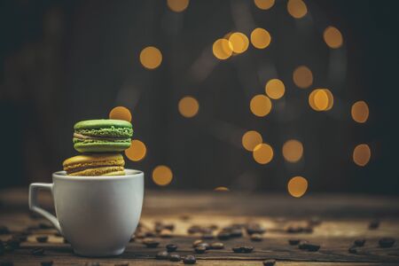 Tasty macaroon cookies with coffee on a wooden table in warm color with beautiful bokehの写真素材