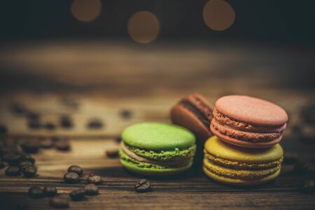 Tasty macaroon cookies with coffee on a wooden table in warm color with beautiful bokehの写真素材