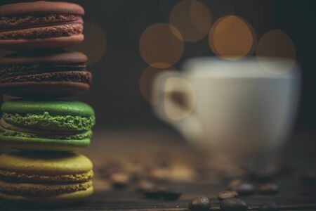 Tasty macaroon cookies with coffee on a wooden table in warm color with beautiful bokeh