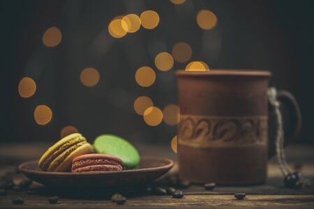 Tasty macaroon cookies with coffee on a wooden table in warm color with beautiful bokehの写真素材