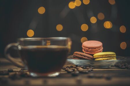 Tasty macaroon cookies with coffee on a wooden table in warm color with beautiful bokehの写真素材