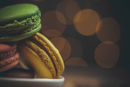 Tasty macaroon cookies with coffee on a wooden table in warm color with beautiful bokehの写真素材