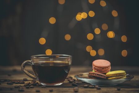 Tasty macaroon cookies with coffee on a wooden table in warm color with beautiful bokehの写真素材