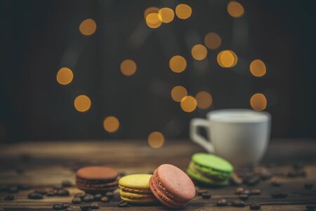 Tasty macaroon cookies with coffee on a wooden table in warm color with beautiful bokehの写真素材