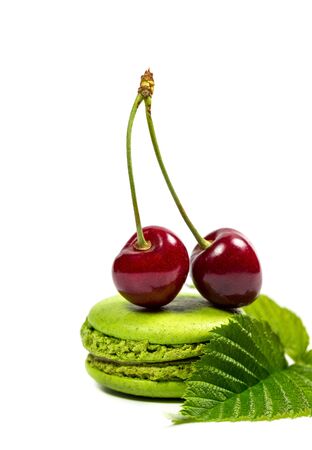 Tasty macaroon cookies and red cherries on a white backgroundの写真素材