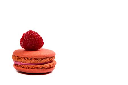 Tasty macaroon cookies and ripe raspberries on a white background