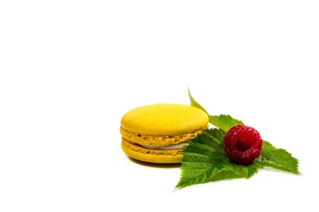 Tasty macaroon cookies and ripe raspberries on a white background
