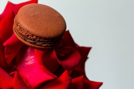 Tasty macaroon cookies and red rose on a white backgroundの写真素材