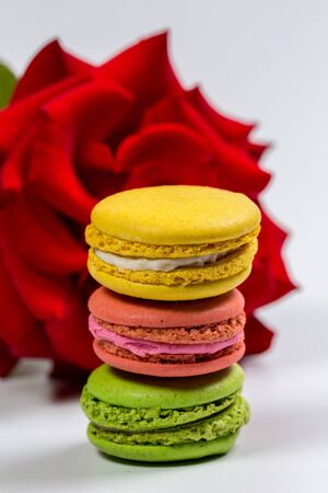 Tasty macaroon cookies and red rose on a white backgroundの写真素材