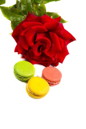 Tasty macaroon cookies and red rose on a white backgroundの写真素材
