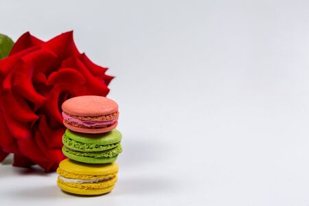 Tasty macaroon cookies and red rose on a white backgroundの写真素材