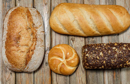 Gluten-free fresh bread of different colors and shapes on wooden surfaceの写真素材