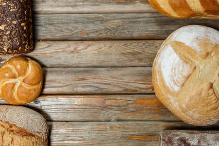 Gluten-free fresh bread of different colors and shapes on wooden surfaceの写真素材