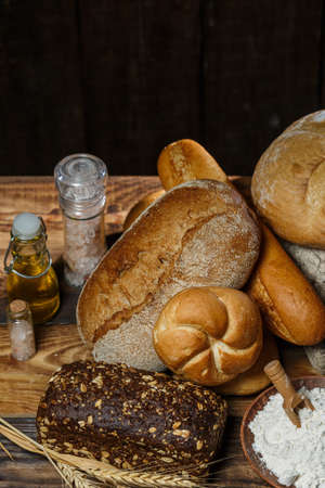 Different loaves of bread cooked with flour and gluten-free wheat on a wooden tableの写真素材