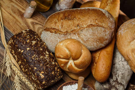 Different loaves of bread cooked with flour and gluten-free wheat on a wooden tableの写真素材