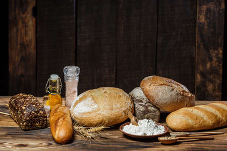 Different loaves of bread cooked with flour and gluten-free wheat on a wooden tableの写真素材