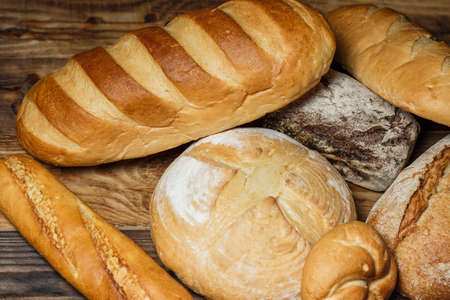 Different loaves of bread cooked with flour and gluten-free wheat on a wooden tableの写真素材