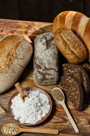 Different loaves of bread cooked with flour and gluten-free wheat on a wooden tableの写真素材