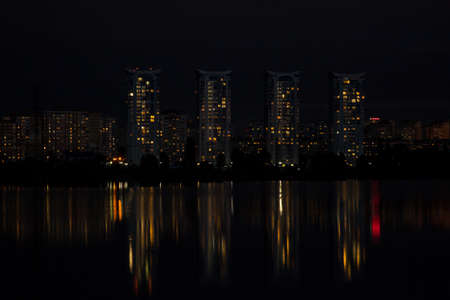 Multi-storey buildings of a big city near the river at nightの写真素材