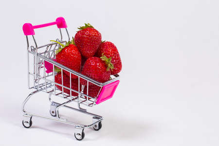 Strawberries in a grocery trolley on a white backgroundの写真素材